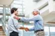 Senior and young executives shaking hands at office