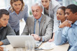 Businessman points at laptop screen while discussing