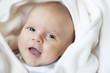 happy baby wrapped in white blanket