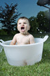 Baby boy taking bath in tub in garden