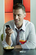 Young man sitting with a glass of orange wine and mobile phone