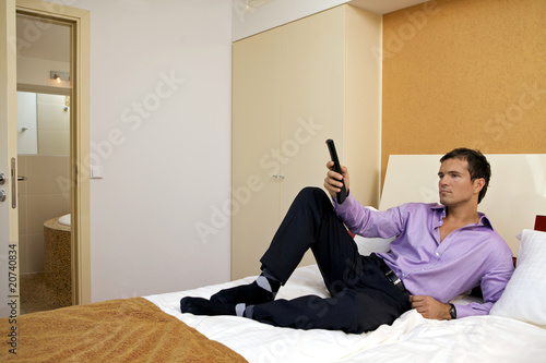 Foto: Man on bed with remote control Man on bed with remote control