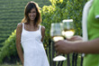 Young woman in vineyard, man bringing glasses of white wine