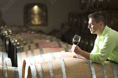 Foto: Young man in wine cellar with glass of red wine Young man in wine cellar with glass of red wine