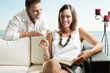 Young man leaning on couch with young woman with book and white wine
