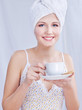 Pretty woman with towel on her head holding cup of coffee