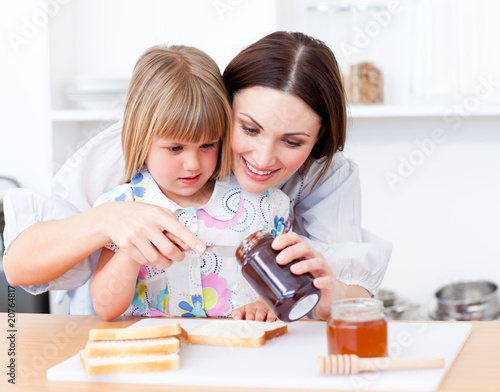Photo: Adorable little girl and her mother preparing toasts Adorable little girl and her mother preparing toasts