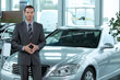 Portrait of car salesperson standing in car showroom