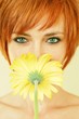 Beautiful woman covering her mouth with a yellow flower