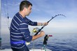 Angler fisherman fighting big fish rod and reel Angler fisherman fighting big fish rod and reel