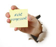 Hand mit Haftnotiz durchbricht Wand