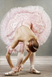 Young dancer in beautiful tutu fixing her slippers