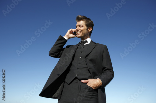 Photo: Young businessman in suit on the phone outdoors Young businessman in suit on the phone outdoors