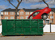 Red car thrown in a green dumpster Red car thrown in a green dumpster