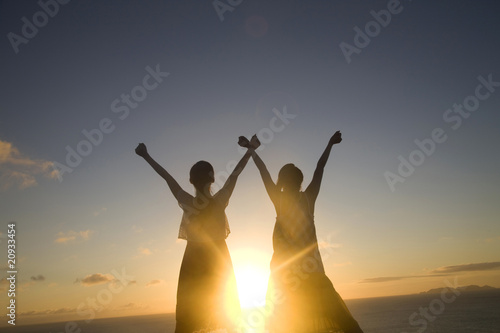 Photo: 夕暮れに両手を空に広げる女性2人のシルエット 夕暮れに両手を空に広げる女性2人のシルエット
