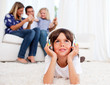 Pensive little boy listening music lying on floor