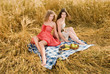 Two beautiful slavonic girls on picnic in wheat field