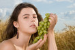 Beautiful slavonic girl on picnic in wheat field with grapes
