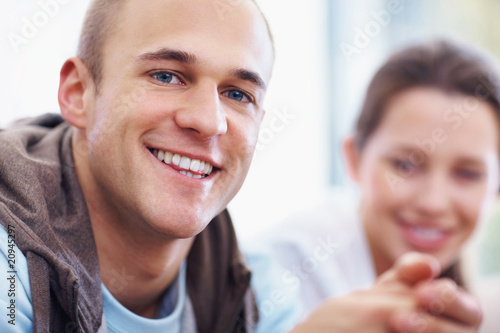 Foto: A smart guy smiling with a beautiful girl in background A smart guy smiling with a beautiful girl in background