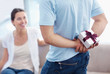 Young man hiding present to gift his lovely girlfriend