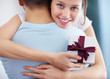 Foto: Cute young girl with a gift in hand hugging her boyfriend Cute young girl with a gift in hand hugging her boyfriend