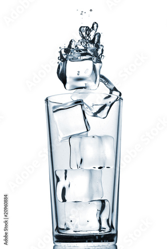 Foto: ice cubes dropped into glass with bubbles isolated on white ice cubes dropped into glass with bubbles isolated on white