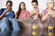 Friends eating popcorn while watching television