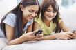 Relaxed girls on couch texting messaging on mobile phone