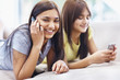 Modern young girls using mobile phone on couch at home