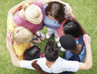 Top view of children forming a huddle on green grass