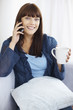Pretty girl talking over the cell phone while drinking coffee