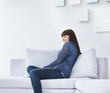 Foto: Happy young woman sitting on the couch at home Happy young woman sitting on the couch at home
