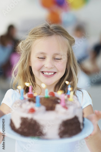 Photo: Little girl holding a birthday cake and making a wish Little girl holding a birthday cake and making a wish