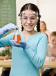 Student holding beaker of liquid in classroom