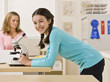 Student looking into microscope in classroom