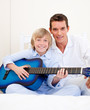 Merry little boy playing guitar with his father Merry little boy playing guitar with his father
