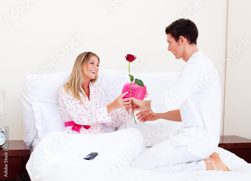 Photo: Adorable husband giving a present to his wife Adorable husband giving a present to his wife