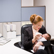Photo: Businesswoman feeding baby at desk Businesswoman feeding baby at desk