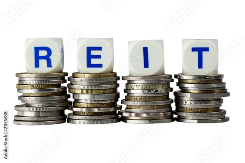Photo: Stacks of coins with the letters REIT isolated on white Stacks of coins with the letters REIT isolated on white