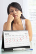 Sad woman with negative pregnancy test and calendar