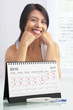 Happy woman with positive pregnancy test and calendar