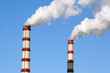 Two huge steaming plant power plant tubes over blue sky