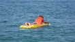 boy dressed in life jacket oaring on inflatable mattress in sea