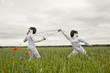 Two girls fencing in a field.