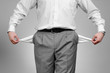 Man pulling out empty pockets on gray background