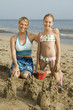 Mother and Young Daughter Building Sand Castle on Beach