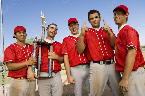 Photo: baseball team-mates holding trophy on field baseball team-mates holding trophy on field