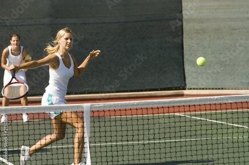 Photo: doubles tennis player hitting tennis ball with backhand doubles tennis player hitting tennis ball with backhand