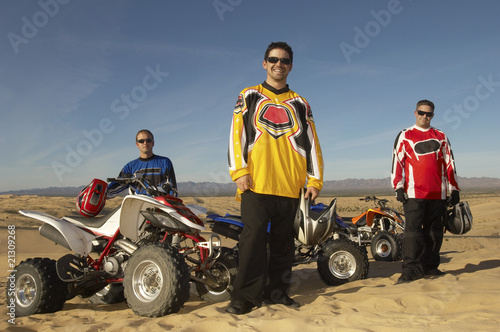 Photo: men standing by quad bikes in desert men standing by quad bikes in desert