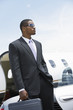 businessman standing beside airplane hand in pocket holding a briefcase